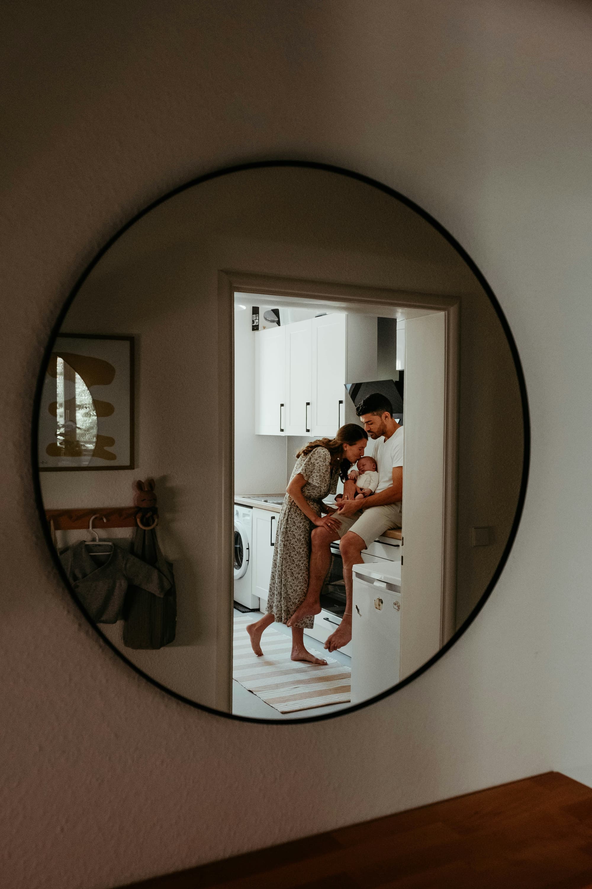 A family with their newborn baby at home, reflected in a mirror